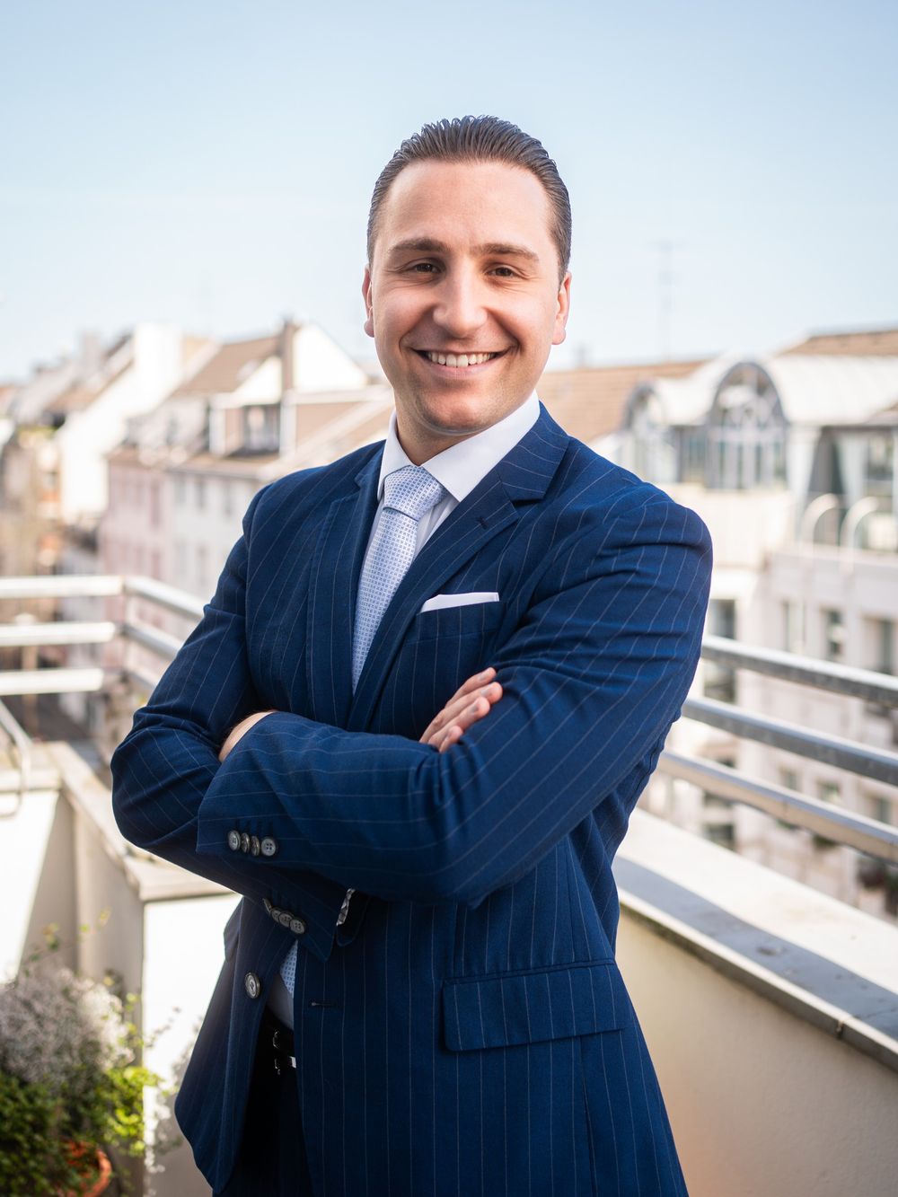 Leonard Bieniek, Finanzcoach in Wuppertal, im blauen Anzug mit verschränkten Armen